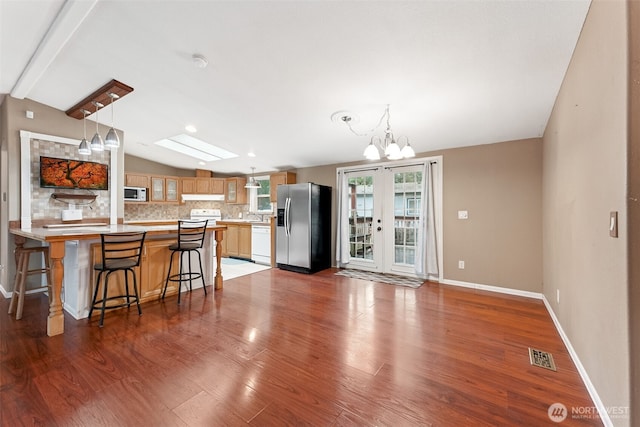 kitchen featuring tasteful backsplash, visible vents, lofted ceiling with skylight, white appliances, and a peninsula