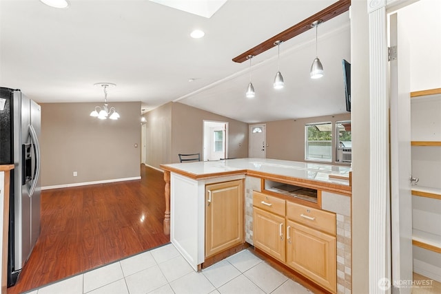 kitchen with open floor plan, stainless steel fridge, vaulted ceiling, and light brown cabinets