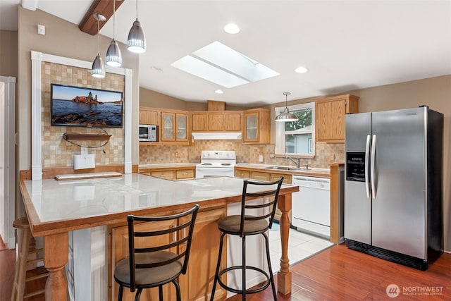 kitchen with stainless steel appliances, light countertops, decorative backsplash, glass insert cabinets, and under cabinet range hood