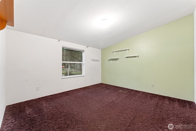 carpeted spare room featuring vaulted ceiling and a textured ceiling