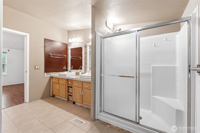 full bathroom with a sink, visible vents, tile patterned floors, double vanity, and a stall shower