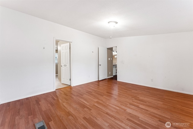 spare room with light wood-style floors, baseboards, and visible vents