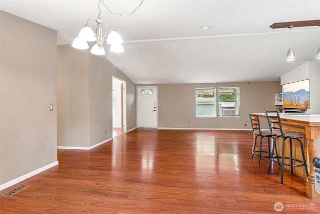 unfurnished living room with lofted ceiling, cooling unit, wood finished floors, visible vents, and baseboards