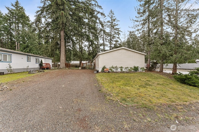 view of property exterior with driveway, fence, and a yard