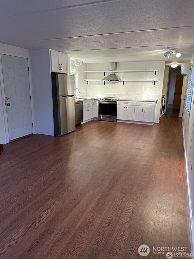 kitchen with white cabinets, dark wood-style flooring, stainless steel appliances, wall chimney range hood, and open shelves