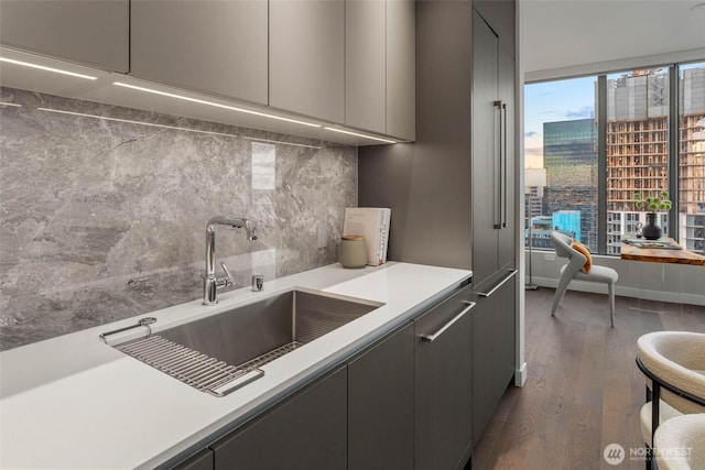 kitchen featuring dark wood-type flooring, a view of city, light countertops, gray cabinetry, and a sink