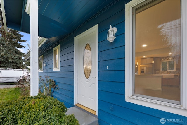 entrance to property featuring a porch and fence