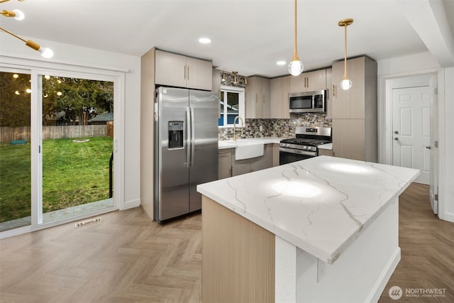 kitchen featuring stainless steel appliances, a healthy amount of sunlight, a sink, and backsplash