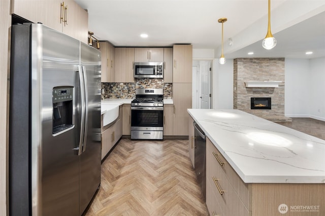 kitchen with hanging light fixtures, backsplash, appliances with stainless steel finishes, open floor plan, and light stone countertops