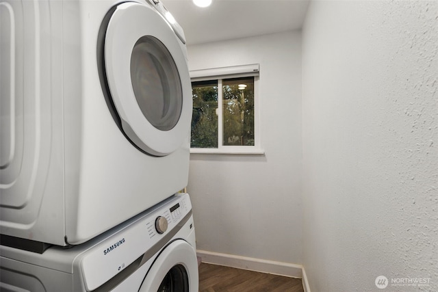 washroom featuring laundry area, dark wood-style flooring, stacked washer and clothes dryer, and baseboards