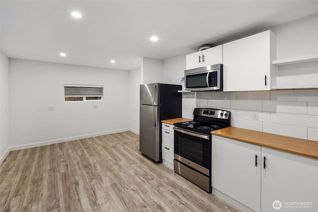 kitchen with open shelves, stainless steel appliances, tasteful backsplash, light wood-style floors, and wood counters