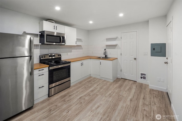 kitchen with open shelves, stainless steel appliances, butcher block counters, a sink, and electric panel