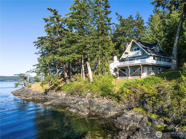 rear view of property featuring a deck with water view and a chimney
