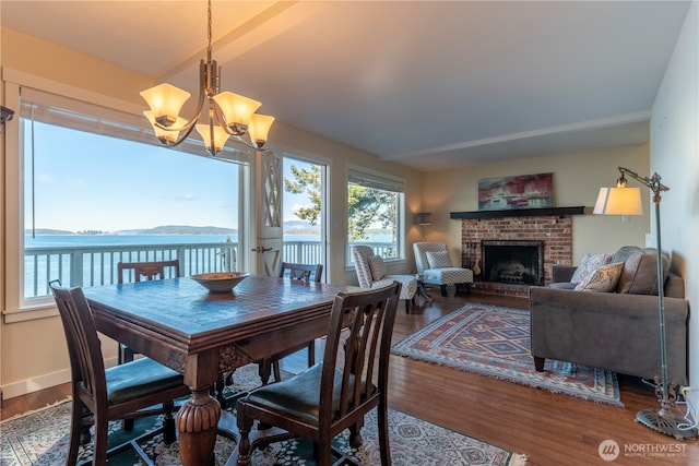 dining space with a fireplace, wood finished floors, baseboards, and a chandelier