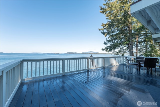 wooden deck with outdoor dining space and a water view