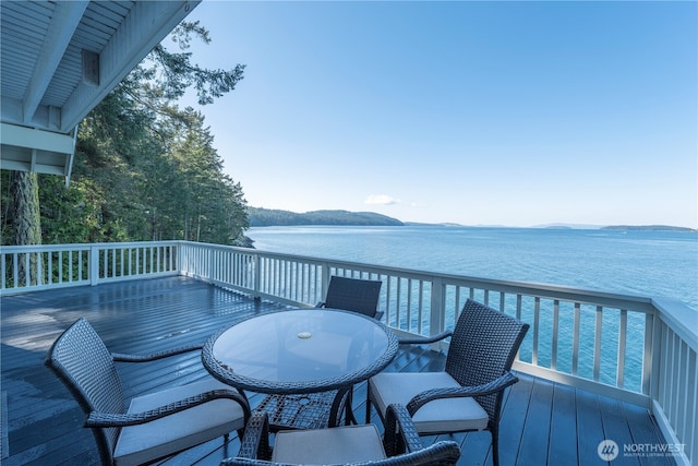 wooden deck featuring a water and mountain view and outdoor dining space
