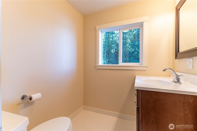 half bathroom with vanity, toilet, and baseboards