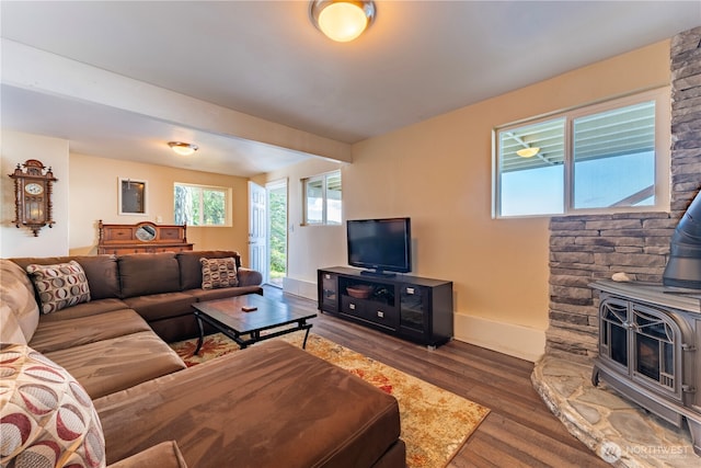 living area with a wood stove, wood finished floors, and baseboards