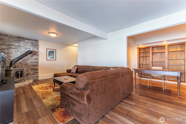 living room with hardwood / wood-style flooring, a wood stove, baseboards, and beam ceiling