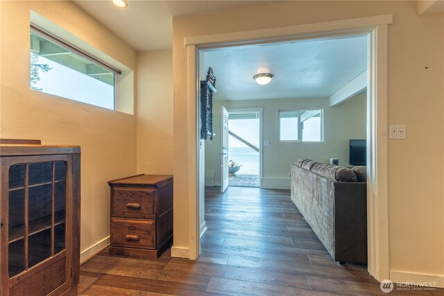 corridor with baseboards and dark wood-type flooring
