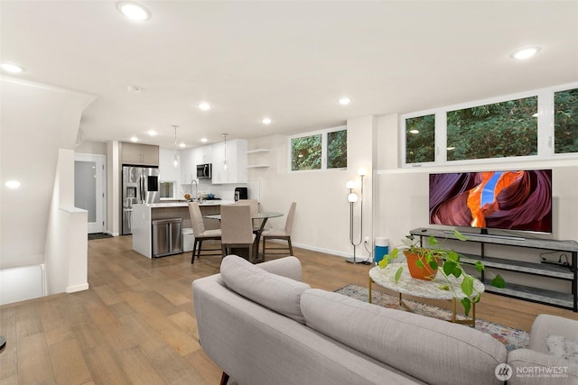 living room featuring light wood-type flooring, baseboards, and recessed lighting