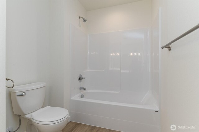 bathroom with toilet, shower / washtub combination, and wood finished floors