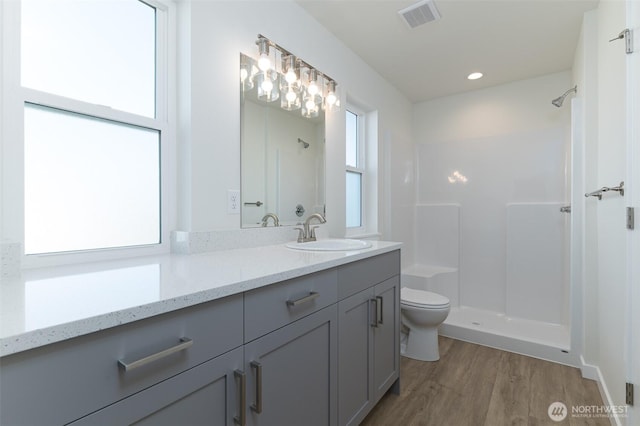 full bath with toilet, wood finished floors, vanity, visible vents, and a shower stall