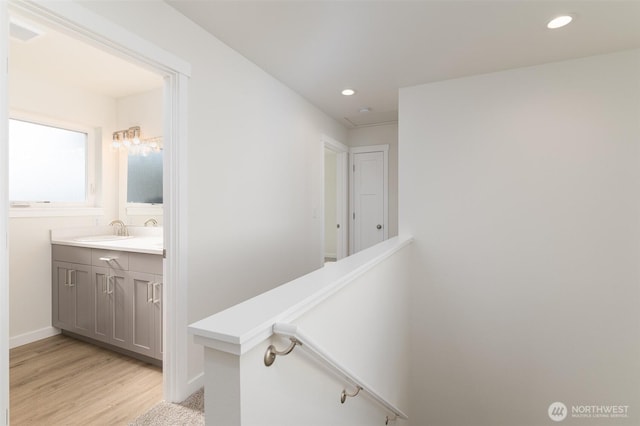 bathroom featuring double vanity, recessed lighting, a sink, wood finished floors, and baseboards