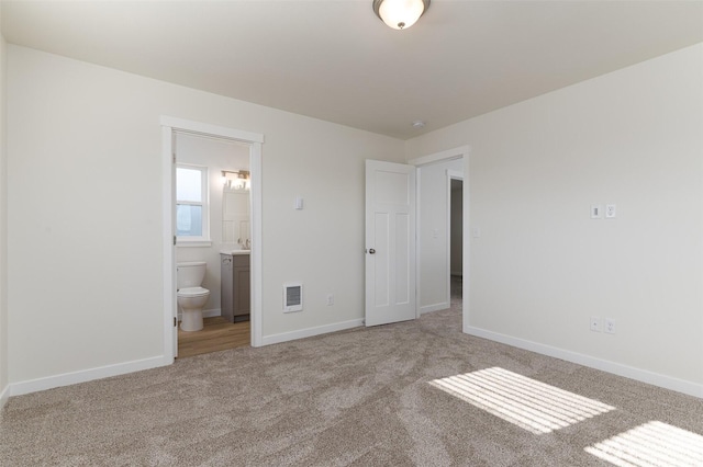 unfurnished bedroom with visible vents, ensuite bath, light carpet, and baseboards