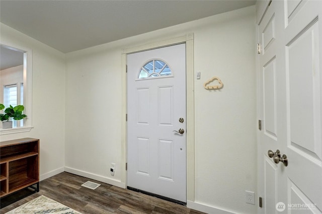 foyer featuring baseboards, visible vents, and dark wood finished floors