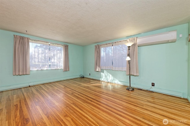 spare room with a baseboard radiator, a wall mounted air conditioner, a textured ceiling, and wood finished floors