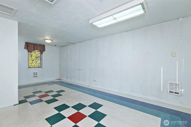 below grade area with baseboards, visible vents, and tile patterned floors