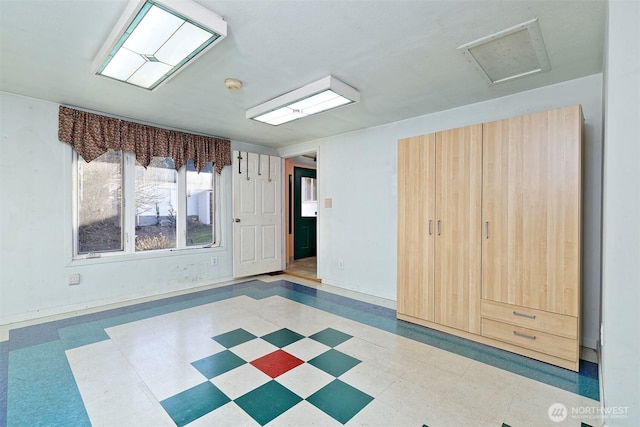 unfurnished room with attic access and tile patterned floors