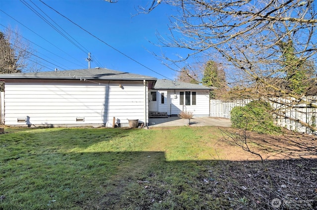 rear view of house with entry steps, a patio, a yard, and fence