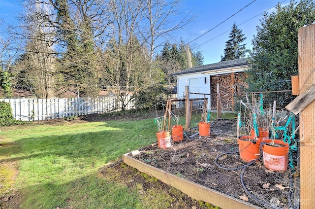 view of yard featuring a vegetable garden, fence, and an outbuilding