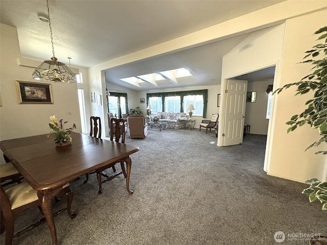 dining area featuring an inviting chandelier, visible vents, dark colored carpet, and lofted ceiling with skylight