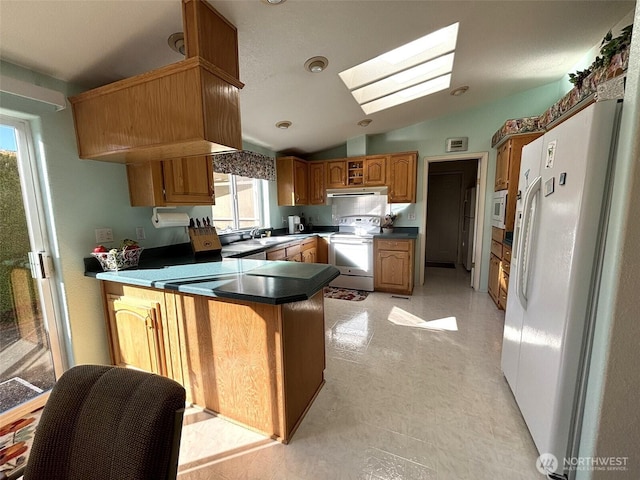 kitchen with white appliances, plenty of natural light, a peninsula, and lofted ceiling with skylight