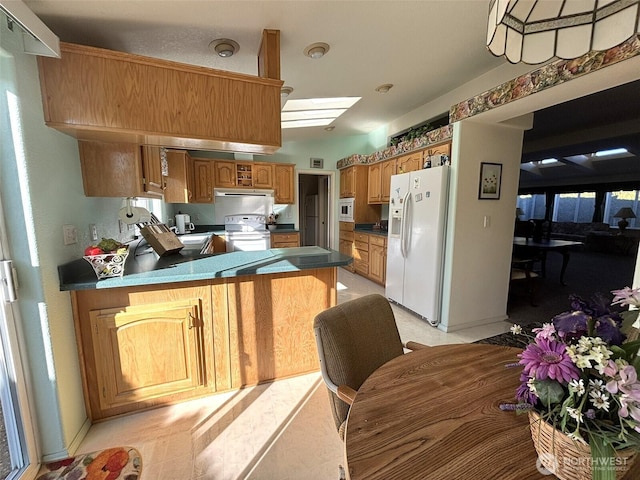 kitchen with white appliances, dark countertops, a peninsula, and extractor fan