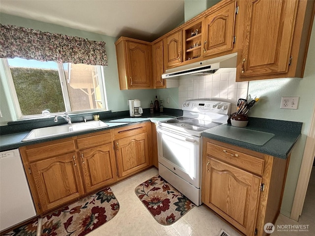 kitchen with under cabinet range hood, decorative backsplash, brown cabinets, white appliances, and a sink