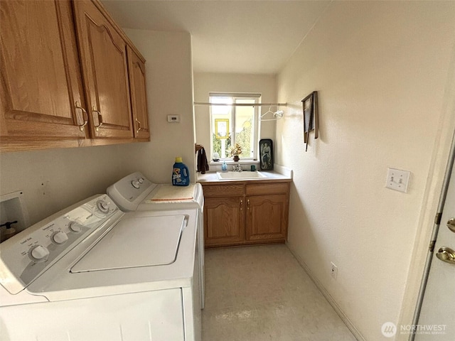 clothes washing area with washer and dryer, baseboards, cabinet space, and a sink