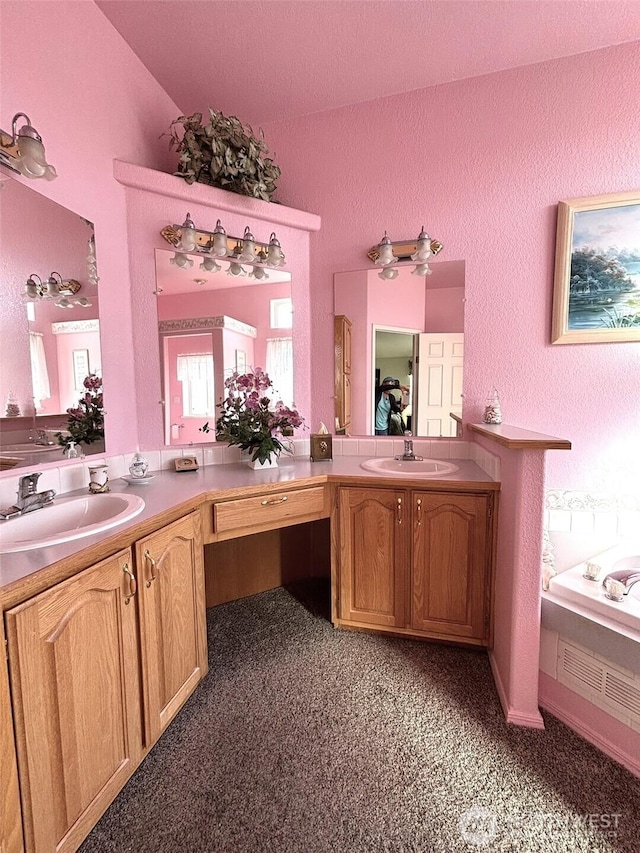 full bath with a sink, two vanities, and a textured wall