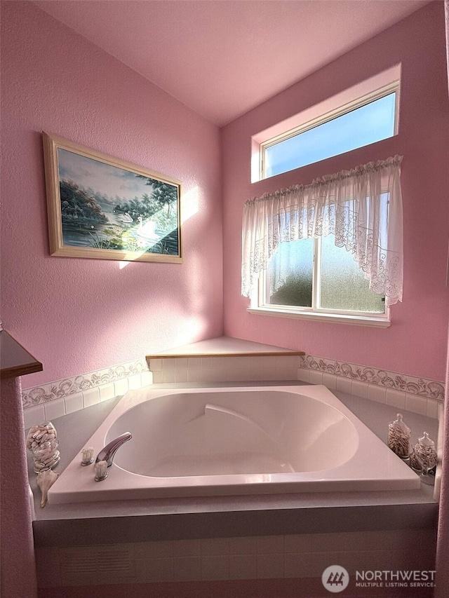 bathroom featuring a garden tub and a textured wall