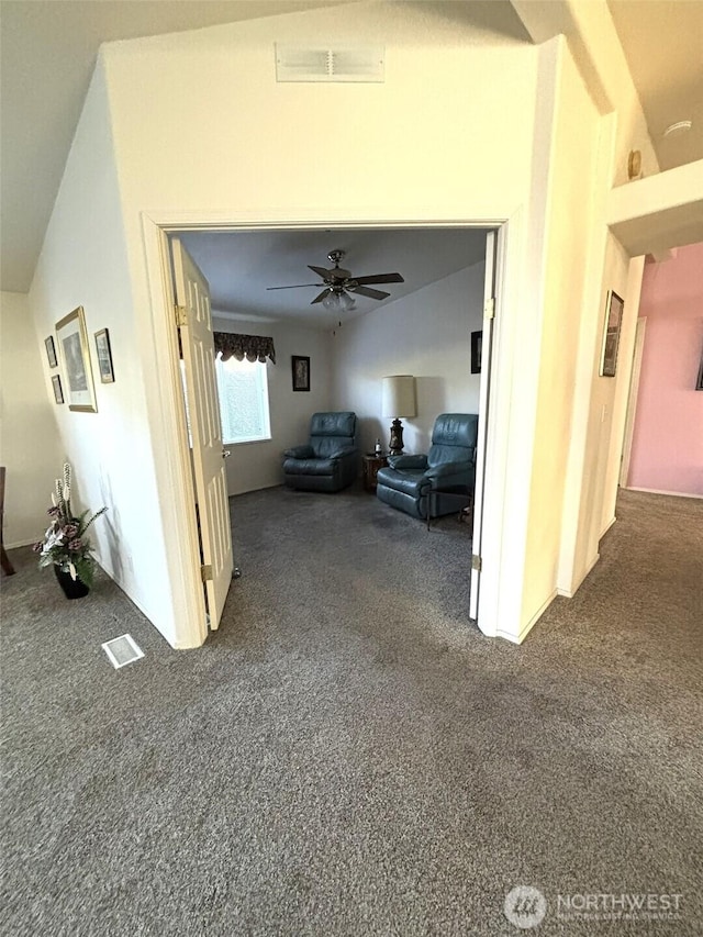 corridor with dark colored carpet, visible vents, and lofted ceiling