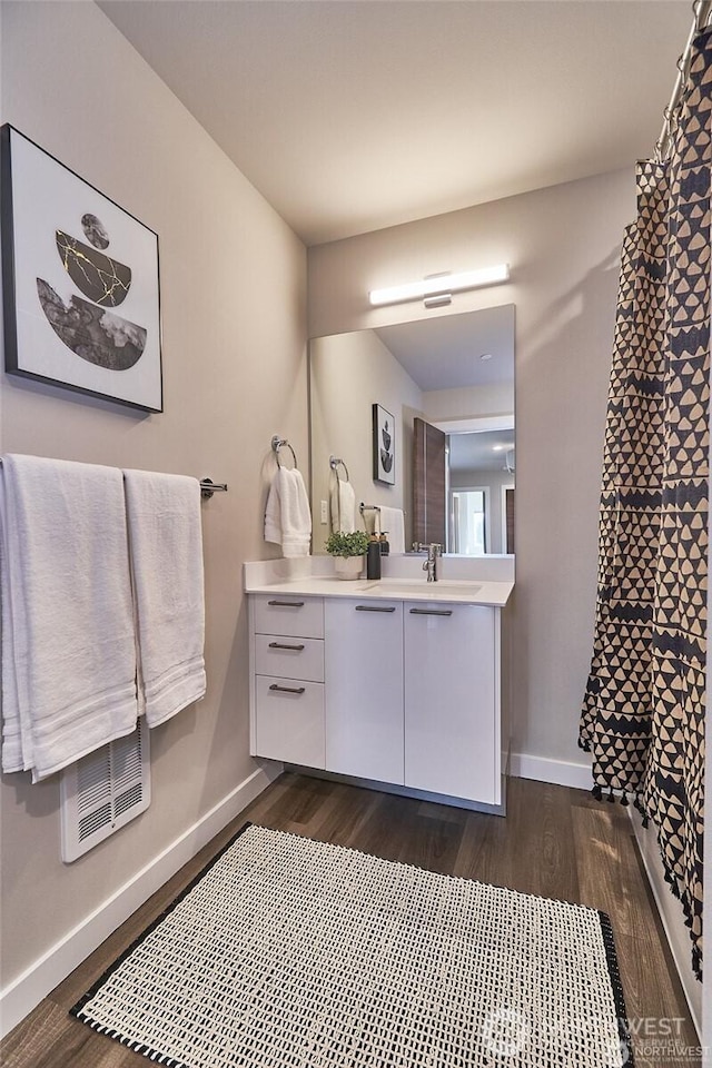 full bath with curtained shower, baseboards, wood finished floors, and vanity