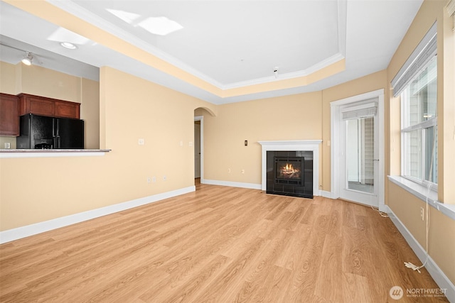 251 W Bakerview Rd Unit 306, Bellingham, WA 98226 - unfurnished living room with a raised ceiling, light wood-style flooring, a tiled fireplace, arched walkways, and ornamental molding