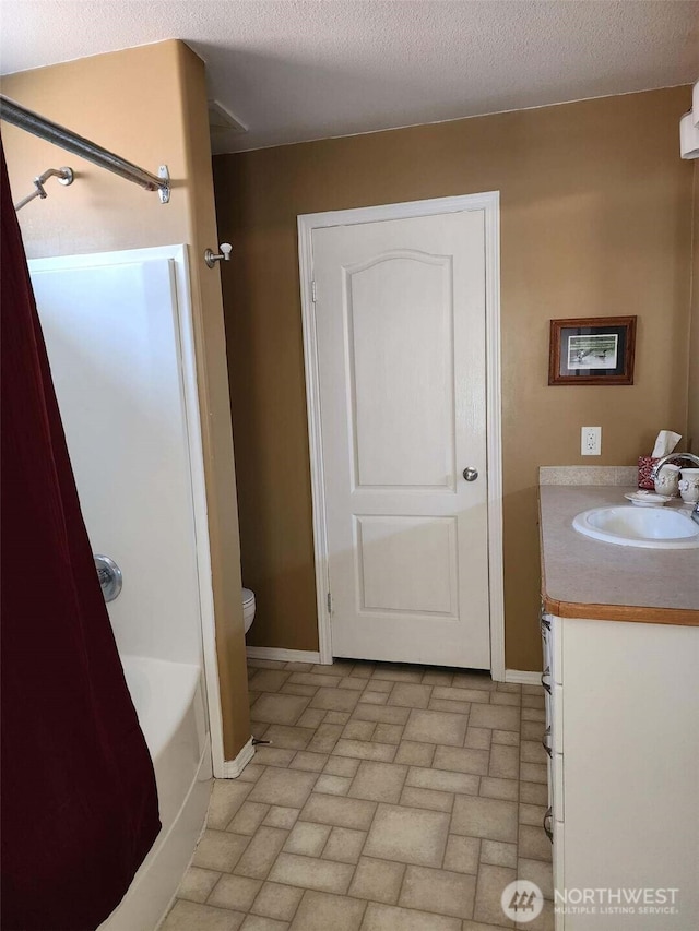 bathroom featuring vanity, toilet, baseboards, and a textured ceiling