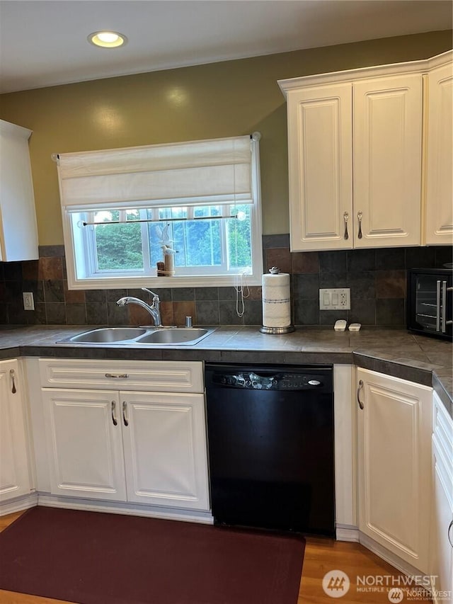 kitchen featuring a healthy amount of sunlight, white cabinetry, a sink, dishwasher, and tasteful backsplash