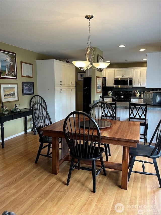 dining area with a toaster, baseboards, and light wood-style floors