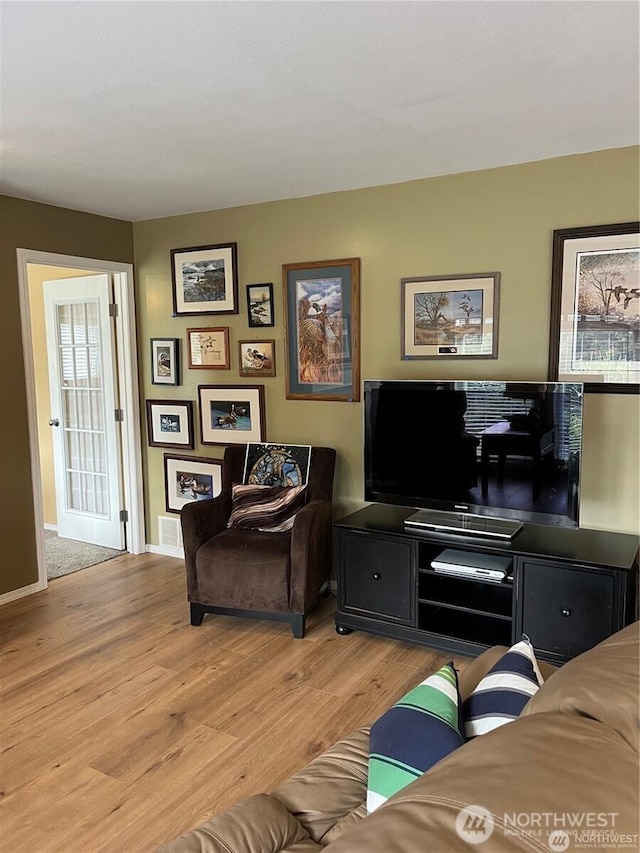 living area with visible vents, light wood-style floors, and baseboards