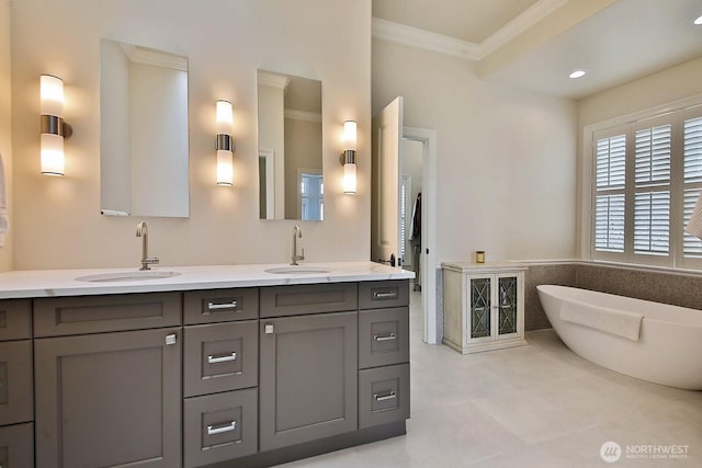 full bathroom featuring a freestanding tub, double vanity, crown molding, and a sink